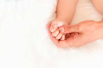 Father holding the hand of his new born son