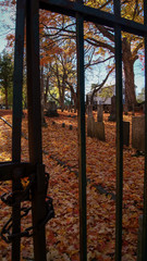 SOUTHBRIDGE, MASSACHUSETS. USA - NOVEMBER 17 2017. View of an old cemetery and graves trough the gate bars in Autumn fall halloween