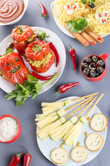 Halloween party food. Red stuffed peppers with scary cutout faces, witches brooms of cheese and other treats
