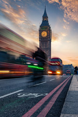 Der Big Ben Turm in London bei Sonnenuntergang und Rushhour mit vorbeifahrendem Bus 