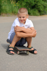 A boy is sitting on a skateboard