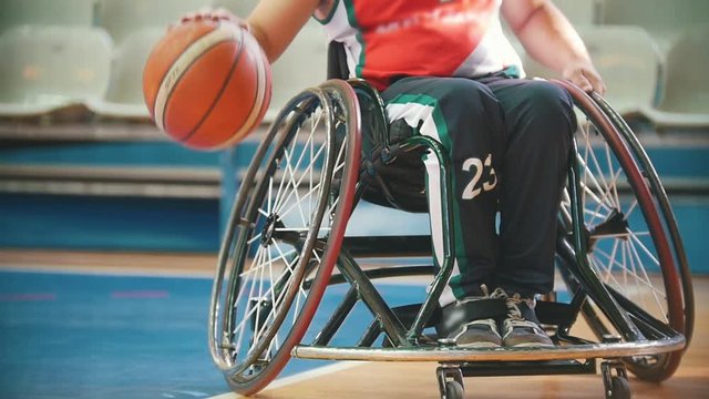 Disabled wheelchair, basketball player practice playing with tha ball in the sport hall