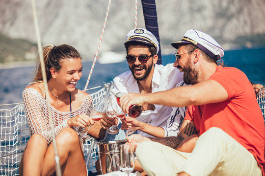 Smiling friends sitting on sailboat deck and having fun.Vacation, travel, sea, friendship and people concept