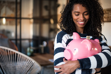 Black woman hugging her piggy bank