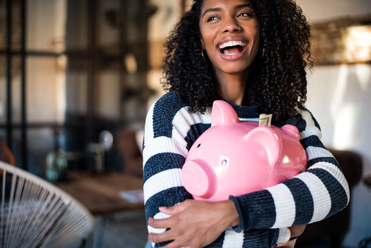 Black woman hugging her piggy bank