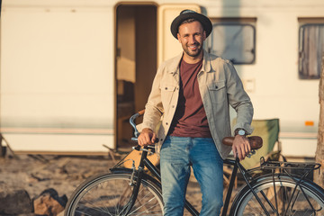 happy handsome man leaning on bicycle near trailer