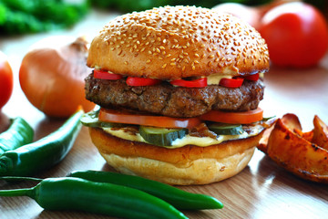Juicy, spicy burger with beef and red pepper, on a table with vegetables