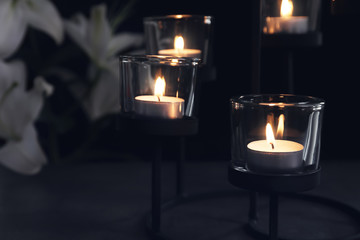 Fototapeta na wymiar Burning candles on dark background. Funeral symbol