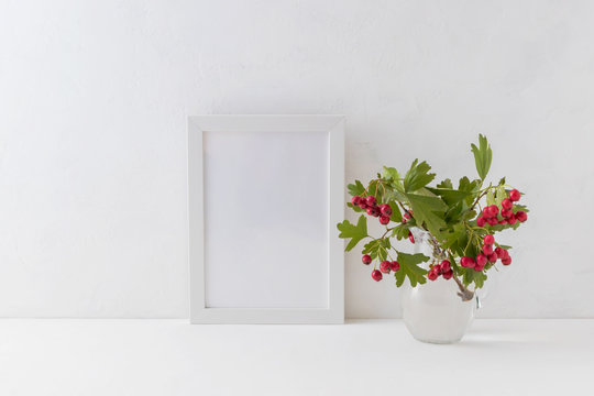 Mockup white frame and branches with red berries in a vase