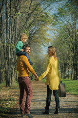 Naklejka na ściany i meble Happy little boy with family go on journey in park. Journey on foot. Where family fun begins