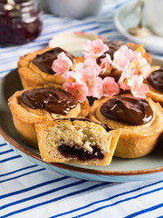 Cakes with frangipane, cherry jam and chocolate frosting. Romantic table setting with flowers. Mother's day card