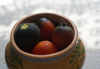 Dark red tomatoes in a clay pot in the kitchen, side view