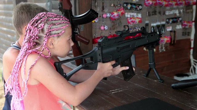 Two children aiming with assault rifle in shooting gallery