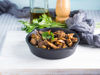 Turkey meat stew with champignon mushrooms and spices served in cast iron skillet on white wooden board