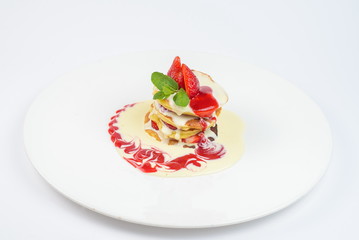 Pancakes with strawberries and sauce on a white plate