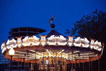 Children's Carousel at an amusement park in the evening and night illumination. amusement park at...