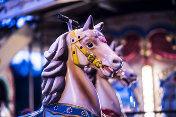 Brilliant vintage merry-go-round wooden horses against the background of Children's Carousel at night time.