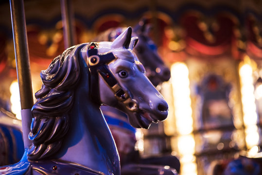 Brilliant vintage merry-go-round wooden horses against the background of Children's Carousel at night time.