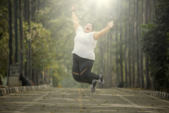 Cheerful fat woman leaping on the road