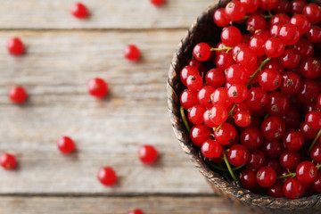 Red currants in wicker basket on grey wooden table