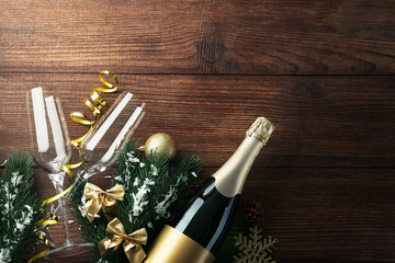 Champagne bottle with glasses and fir-tree branches on brown wooden table
