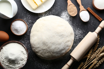 Raw dough with flour and rolling pin on wooden table