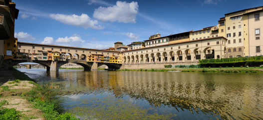 Naklejka premium The famous Ponte Vecchio and Uffizi gallery in Florence reflected on the waters of the river Arno. Italy.
