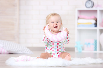 Baby girl sitting on white carpet with soft toy
