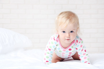 Baby girl on white bed at home