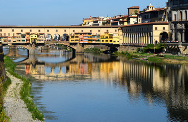 Naklejka premium The famous Ponte Vecchio and Uffizi gallery in Florence reflected on the waters of the river Arno. Italy.