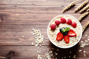Oatmeal with berries in bowl on brown wooden table