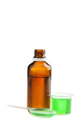 Bottle, measuring plastic cup and spoon with medical syrup on white background