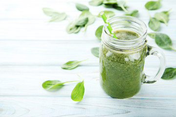 Spinach smoothie in glass jar on wooden table
