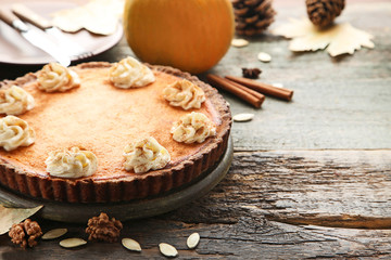 Pumpkin tart with whipped cream, seeds and walnuts on wooden table