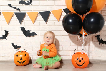 Baby girl in halloween costume with pumpkin buckets and balloons