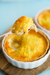 Gluten free leek mini quiches on a wooden board served with fresh rukkola, tomatoes and cheese