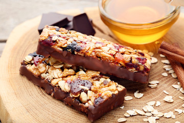 Tasty chocolate granola bars with honey in bowl on wooden table