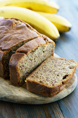 Banana bread on a wooden board served with fresh bananas