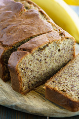Banana bread on a wooden board served with fresh bananas