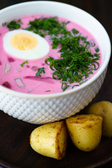 Lithuanian Saltibarsciai (Cold Beet Soup) with a hard boiled egg and new potatoes on a wooden background