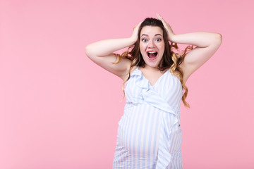 Fototapeta premium Beautiful pregnant woman in striped dress on pink background