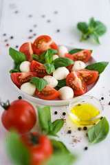 Caprese salad served on a white ceramic plate. White wooden background, high resolution