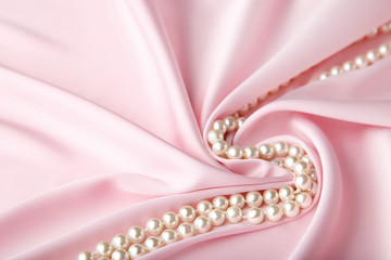 Pearl necklace on pink satin fabric