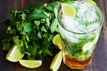 Dirty mojito and ingredients (fresh mint, sliced lime) served on a dark wooden board. High resolution.