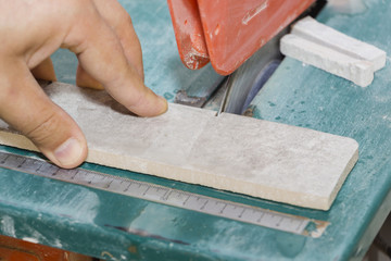 master cuts the tiles on the saw. repair of apartments and houses.
