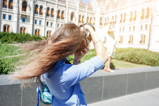 Portrait of a young women tourist with photo camera in front of the famous Parliament building traveling in Budapest city, Hungary