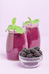 Obraz na płótnie Canvas Blackberry smoothie - raw organic drink with fresh ripe forest berries on pastel violet background.