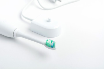 A part of electrical toothbrush with charger on white background, close up view