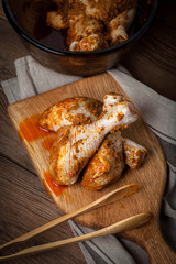 Marinated chicken drumsticks on a wooden chopping board.