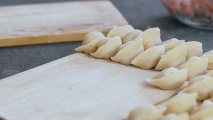 Dumplings with mince meat on a wooden board. Close-up view